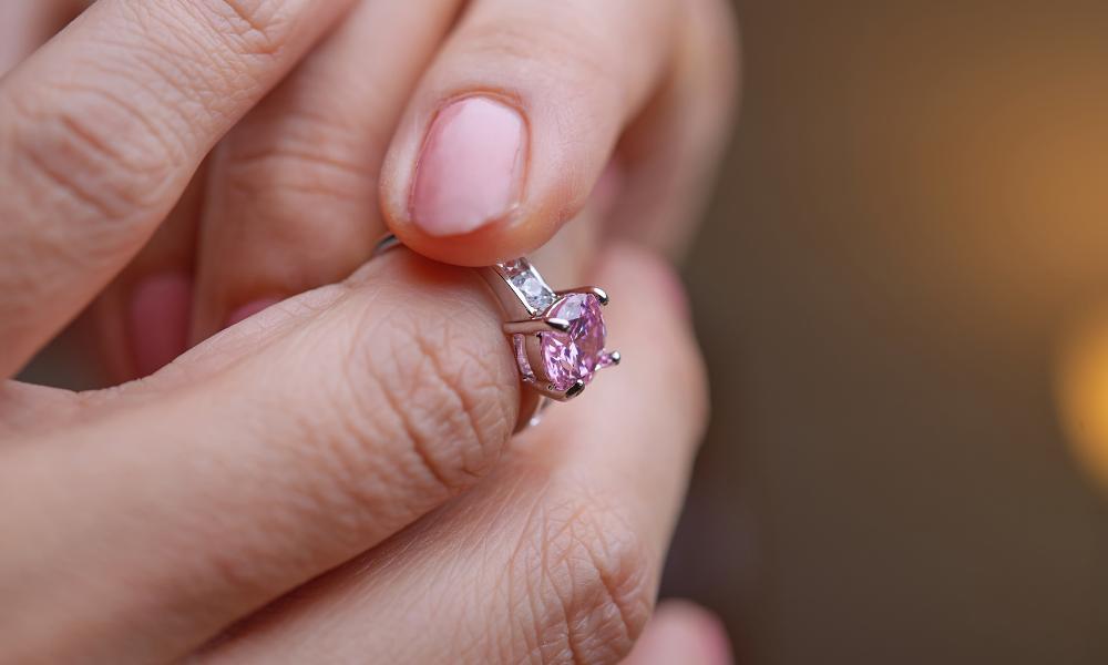 a person holding a pink sapphire ring
