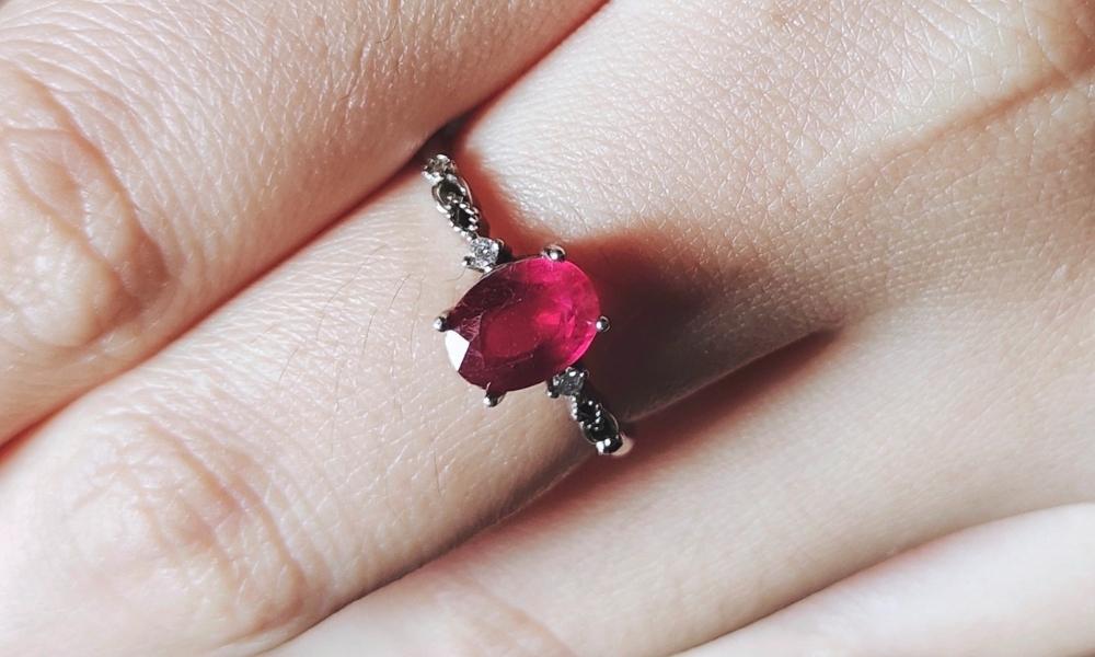 a hand with a  rhodolite garnet ring on it