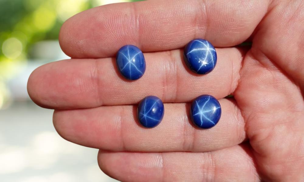 a hand holding blue star sapphire stones