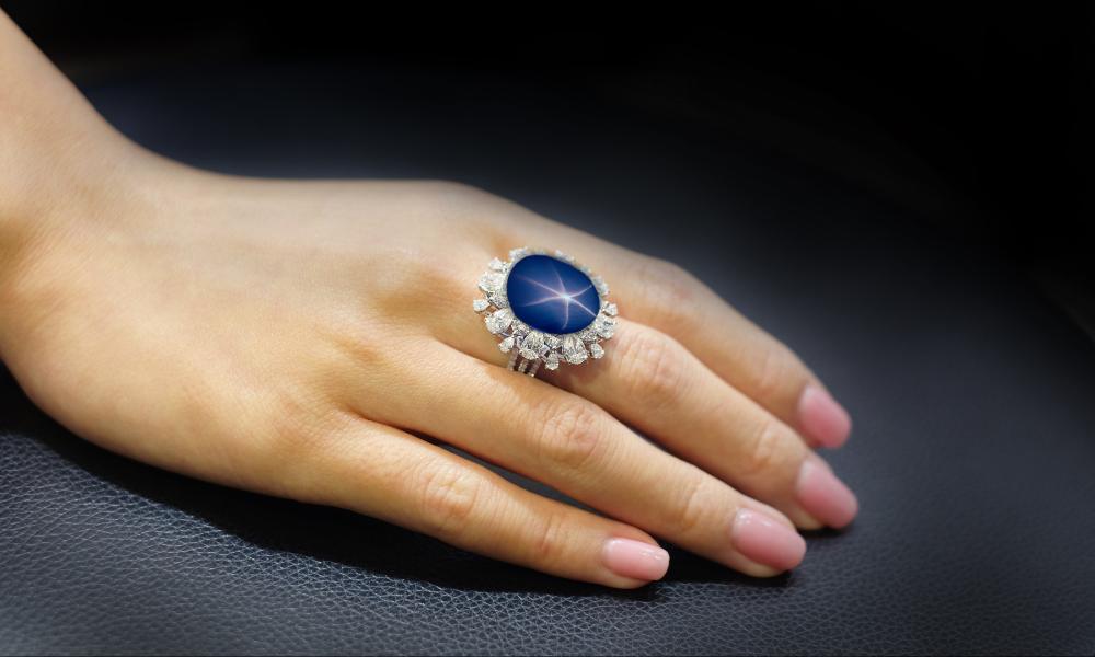a hand with a blue sapphire ring on it
