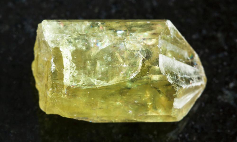 a yellow apatite on a black surface