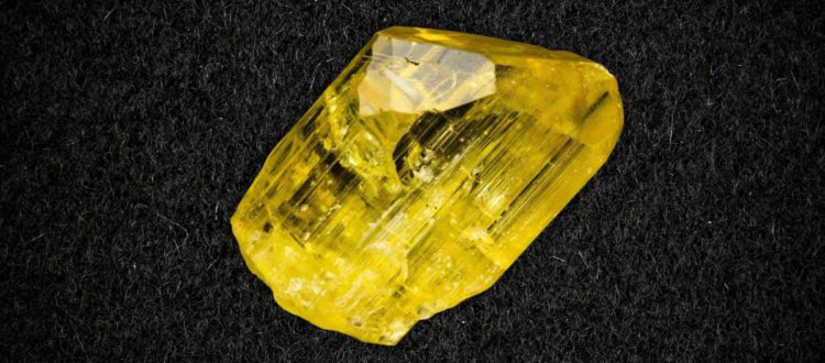 a yellow crystal on a black surface