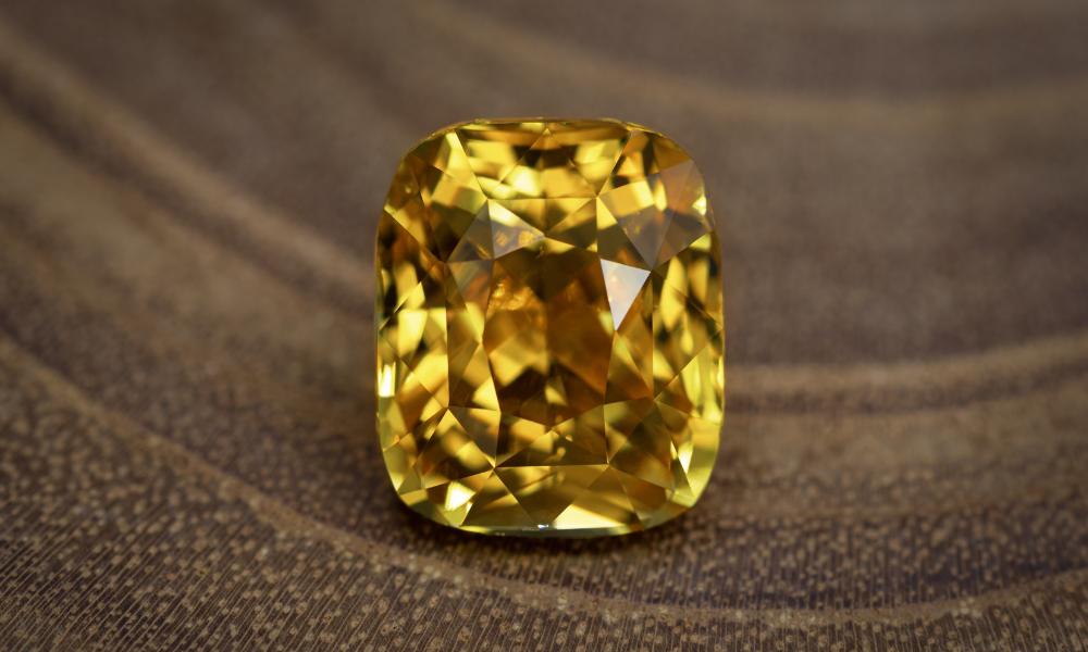a yellow sapphire on a wood surface
