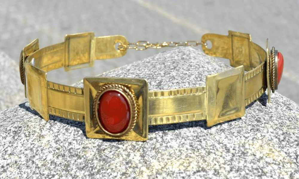 a gold bracelet with a red agate on it