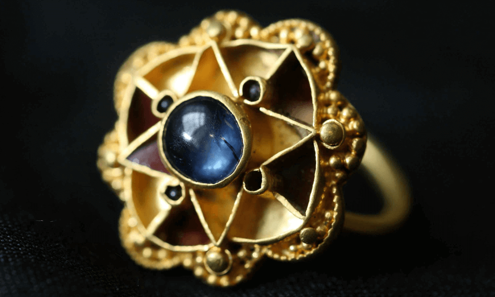 a close up of a vintage sapphire ring on a black surface
