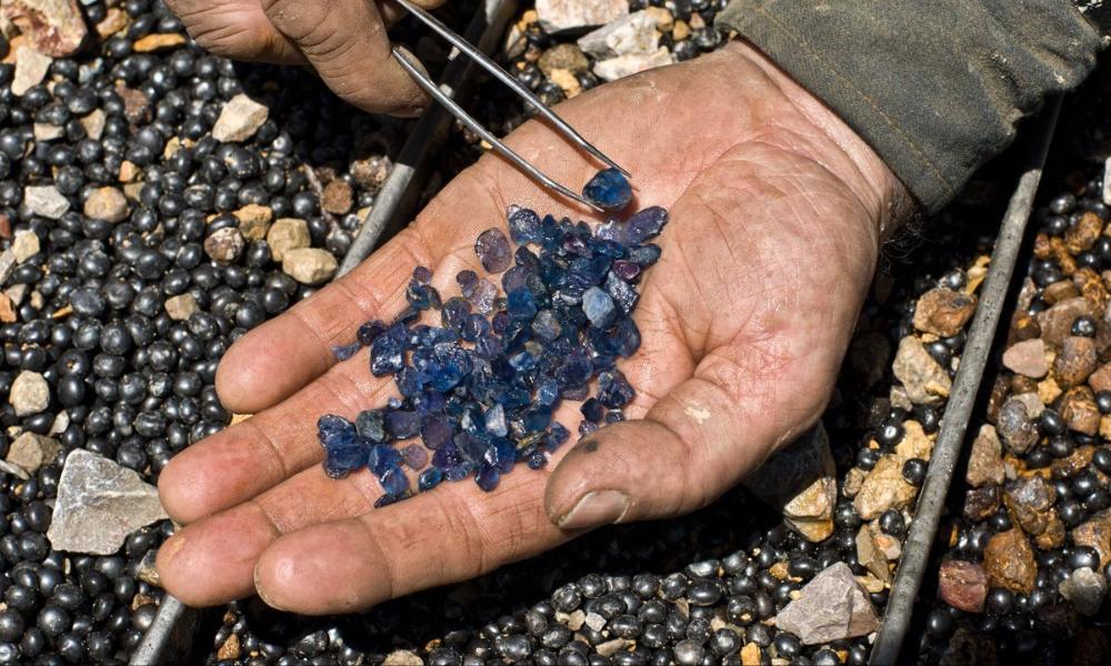 a person holding a bunch of blue sapphires in their hand