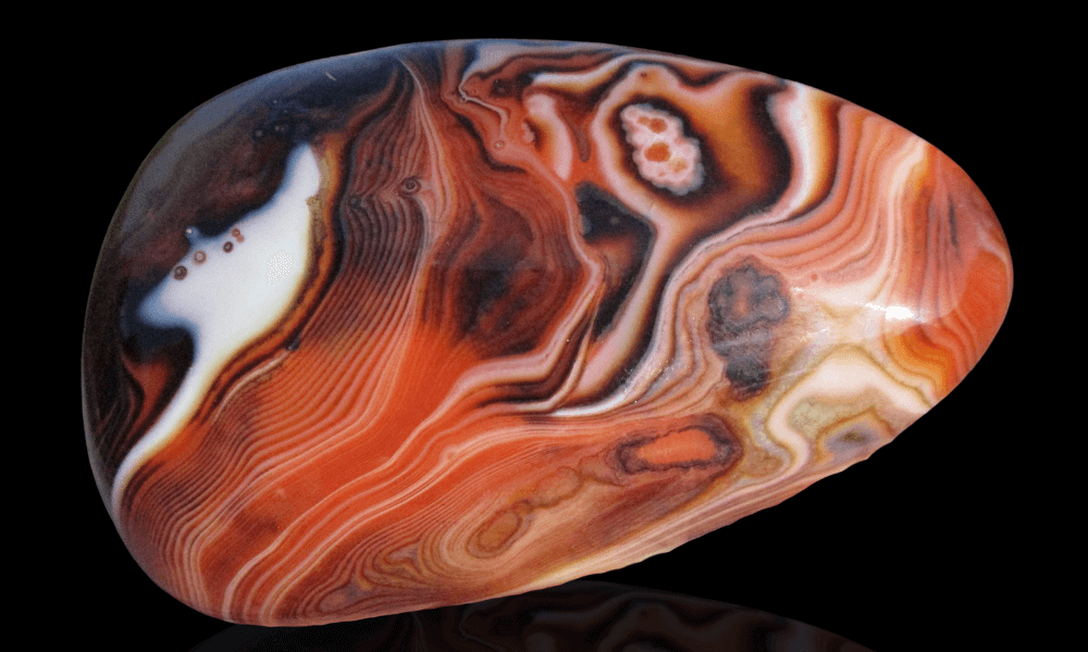 an orange and white red agate on a black background