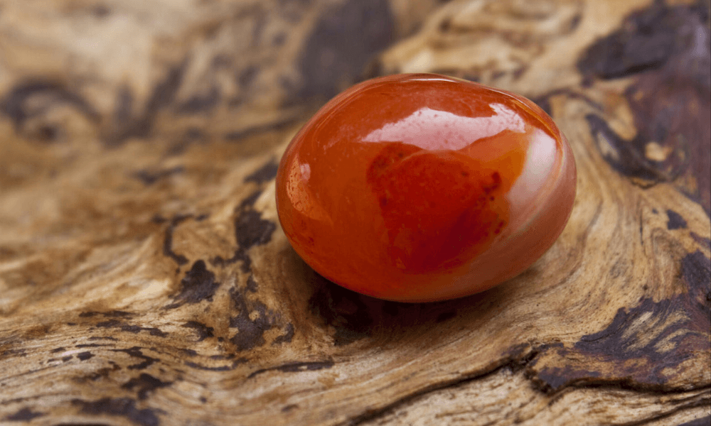 a red agate sitting on top of a piece of wood
