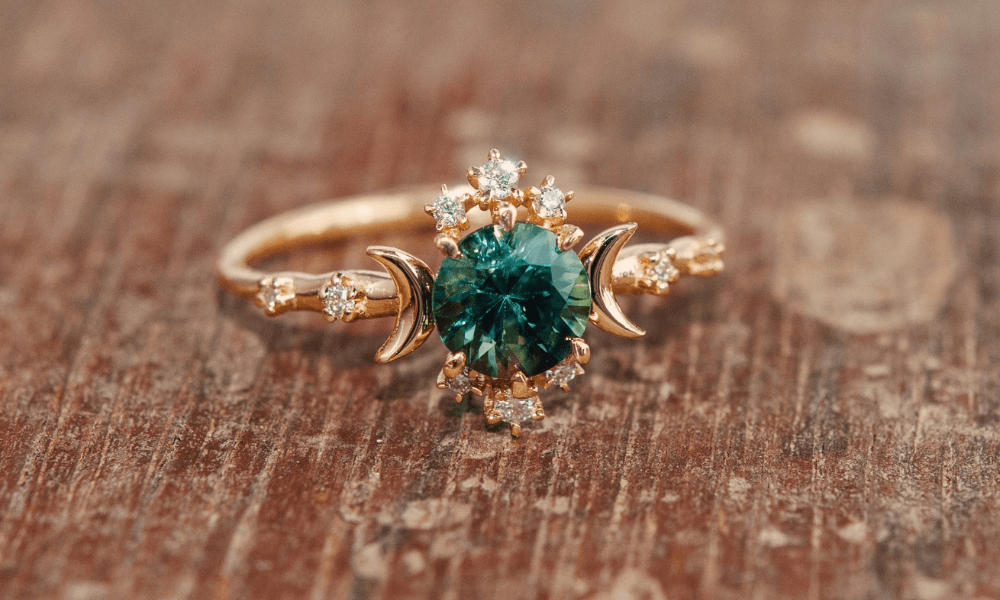 a close up of a green sapphire ring on a wooden surface