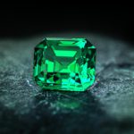 green gemstone on rock and black surface