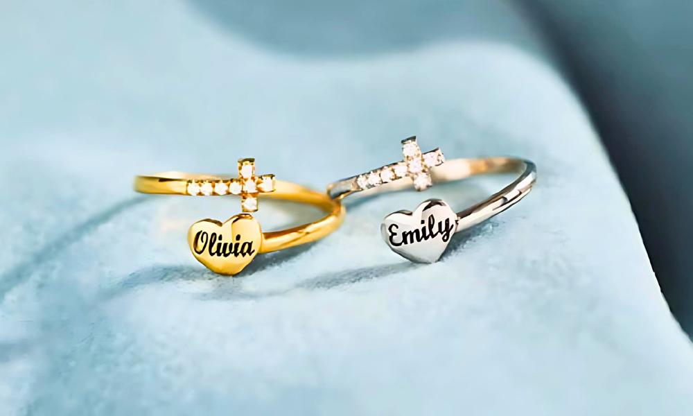 Two personalized rings with names "Olivia" and "Emily" on heart-shaped insets, one gold and one silver.