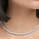 a close-up of a diamond tennis necklace on a mannequin's neck with short hair.