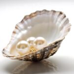 Three pearls resting inside an open seashell with a reflective surface.