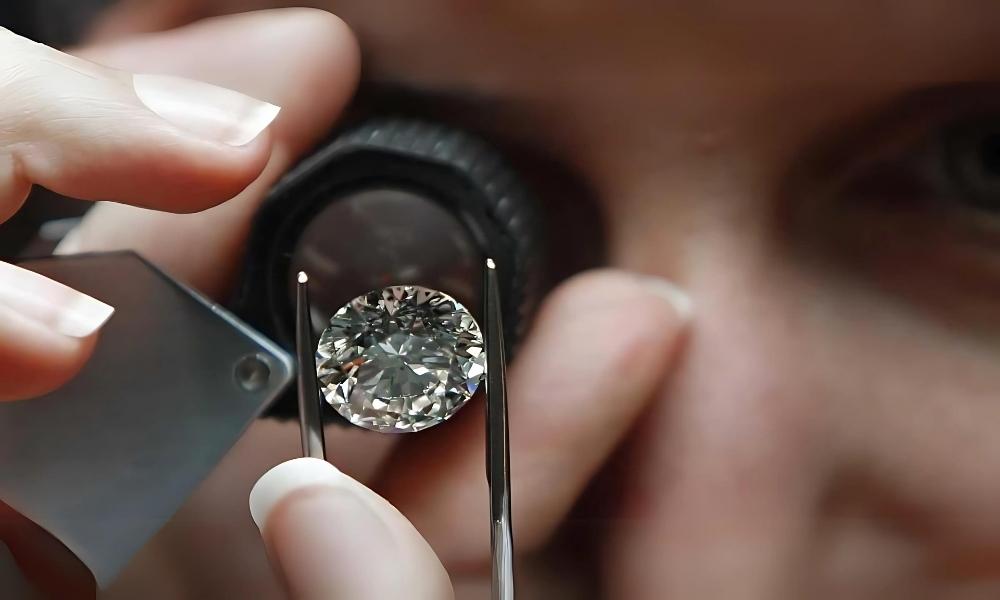 A person examines a large diamond closely with a jeweler's loupe.