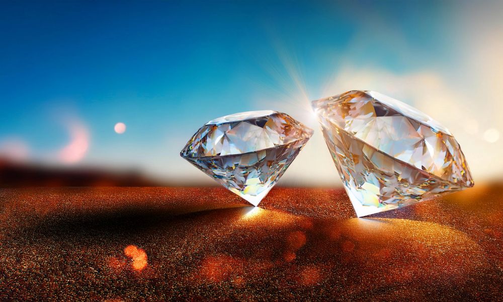 Two sparkling diamonds on a glittery surface with a blue sky background.