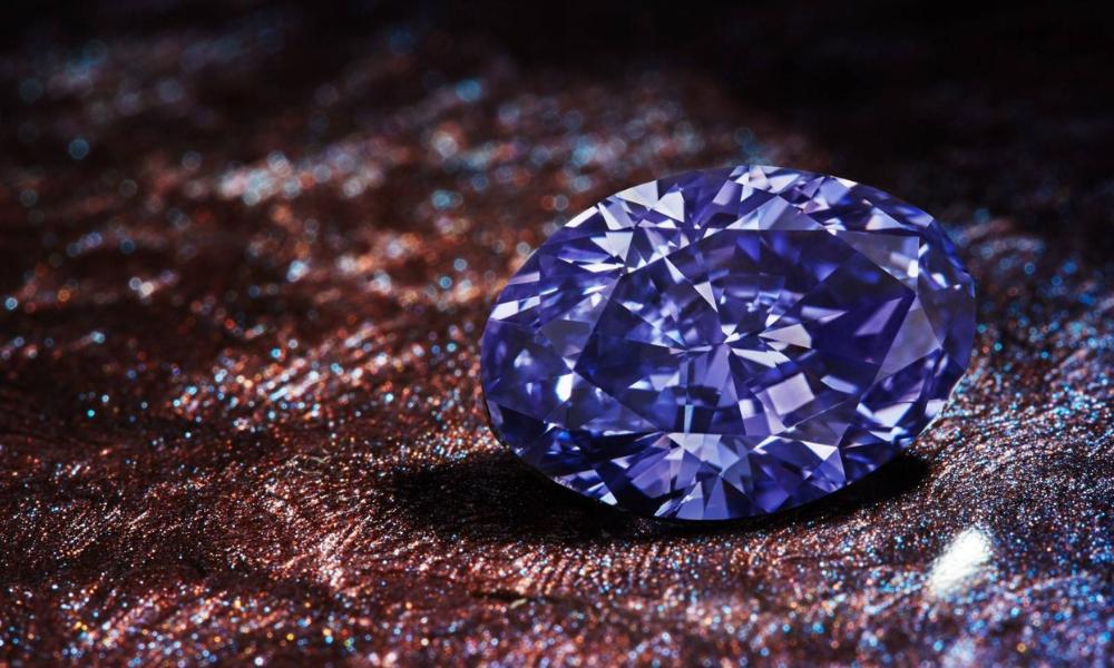 A radiant purple diamond on a glittery brown surface.