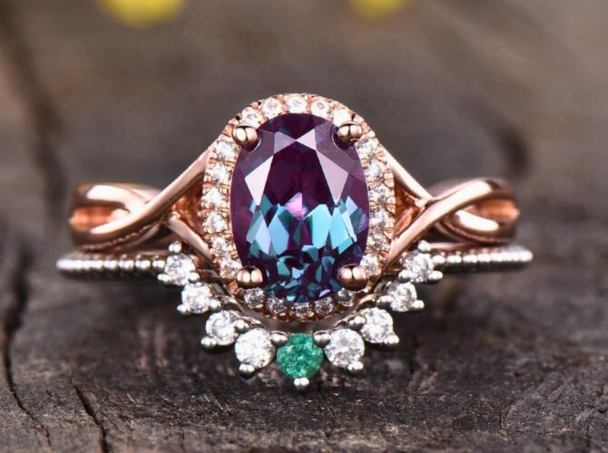 Oval-cut alexandrite rings with diamond accents on a rose gold band against a wooden backdrop.