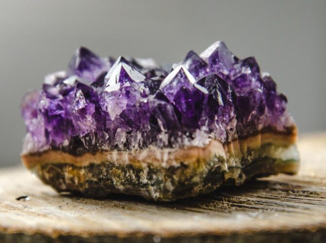 A chevron amethyst geode on a wooden surface, showcasing sharp purple crystals.