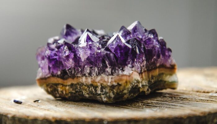 A chevron amethyst geode on a wooden surface, showcasing sharp purple crystals.