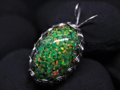 A glittering green opal wrapped in a wire setting against a dark background.