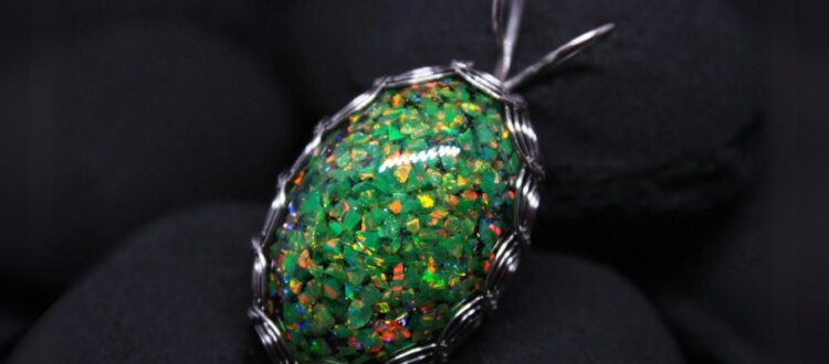 A glittering green opal wrapped in a wire setting against a dark background.