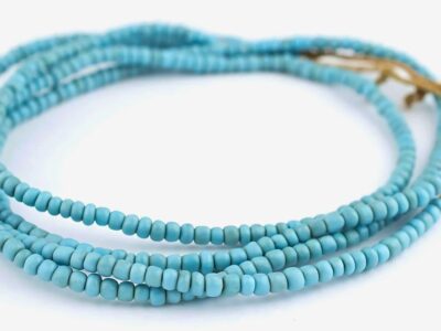 A multi-strand heishi beads necklace with a gold clasp on a white background.