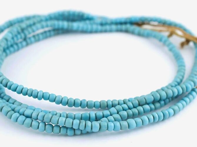 A multi-strand heishi beads necklace with a gold clasp on a white background.