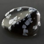 Snowflake obsidian with black and white speckled pattern on a grey background.